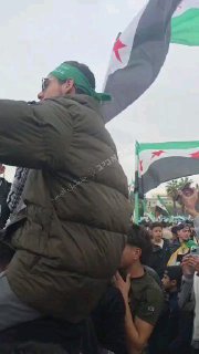 דמשק אמש: סוני עוטה סרט ראש של חמאס ומניף דגל חמאס, שסביבו...