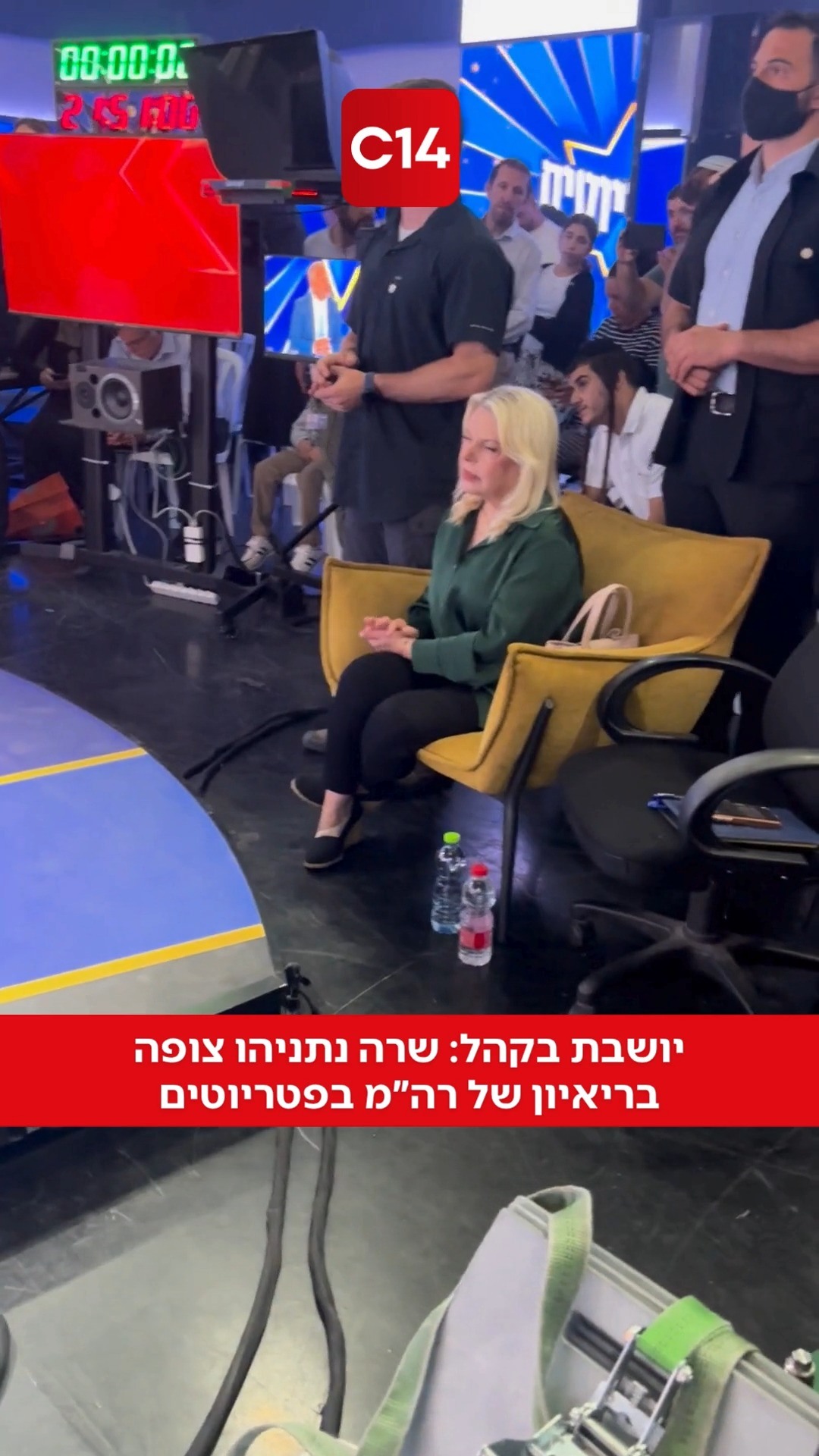 ⁨ יושבת בקהל: שרה נתניהו צופה בריאיון של רה"מ בפטריוטים⁩...